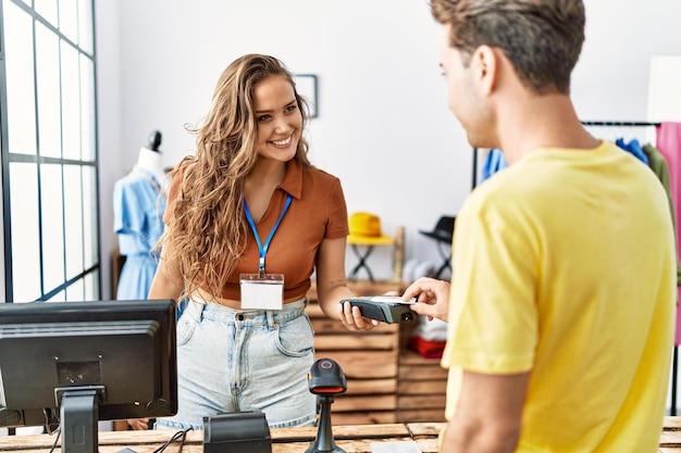 Man and woman paying purchase using credit card and data phone at clothing store