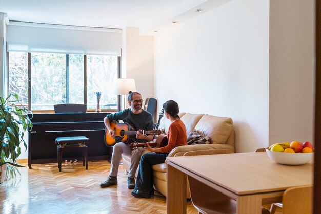 Photo man and woman playing guitar at home