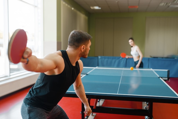 Man and woman playing ping pong, focus on racket