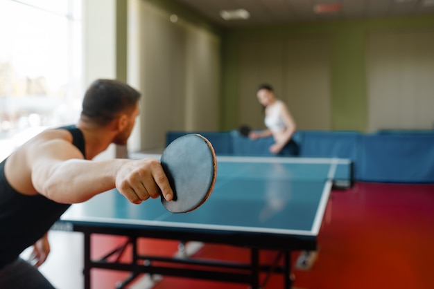 Man and woman playing ping pong indoors