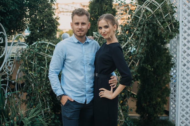 A man and a woman pose in front of a plant