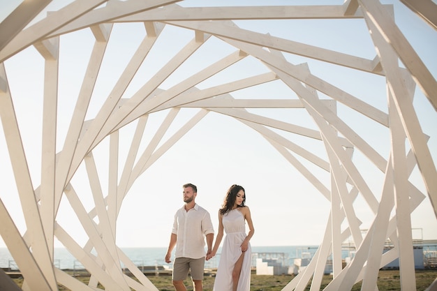 Man and woman posing. Geometric wooden structures. The bride and groom.