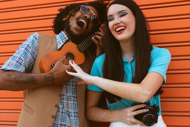 Photo man and woman posing together in retro style with ukulele and camera