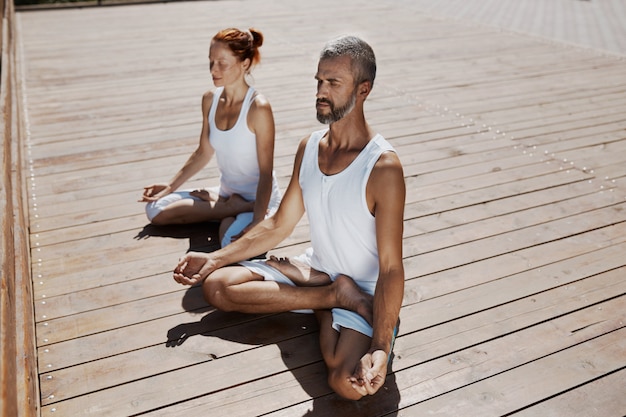 Man and woman practicing relaxing yoga in the park