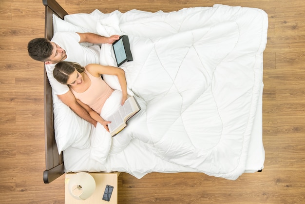 Foto l'uomo e la donna leggevano sul letto. vista dall'alto