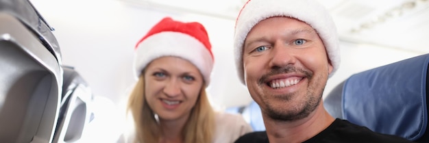 Man and woman in red santa hats flying in airplane