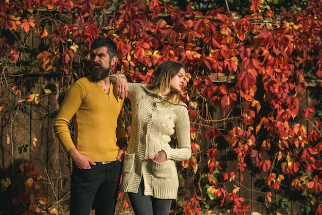 Man and woman at red tree leaves.