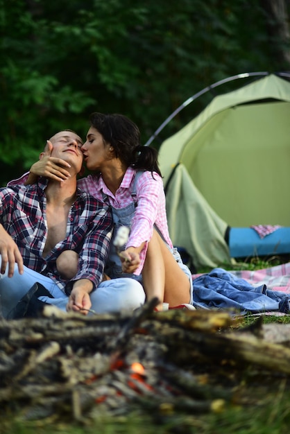 Man and woman relaxing near firebone and camping tent travel love and living in nature concept sensu