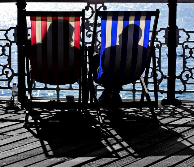 Man and woman resting on deck chairs at pier