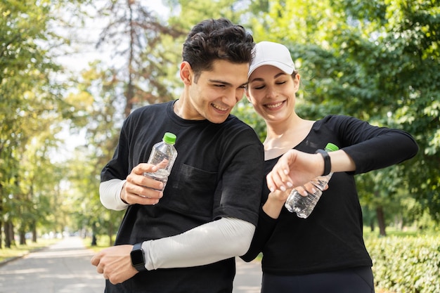 A man and a woman running couple do sports and drink water a\
healthy lifestyle fitness watch on hand