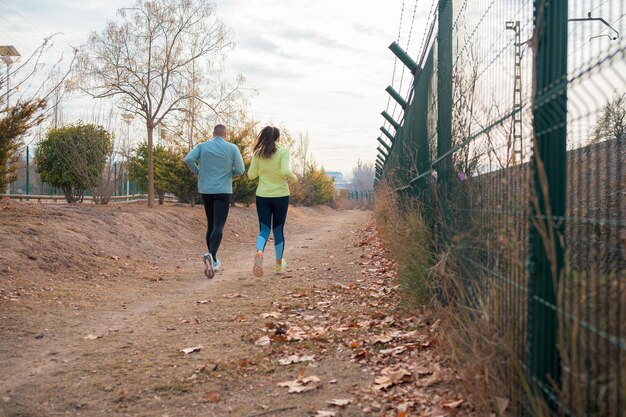 Photo a man and a woman running in a park