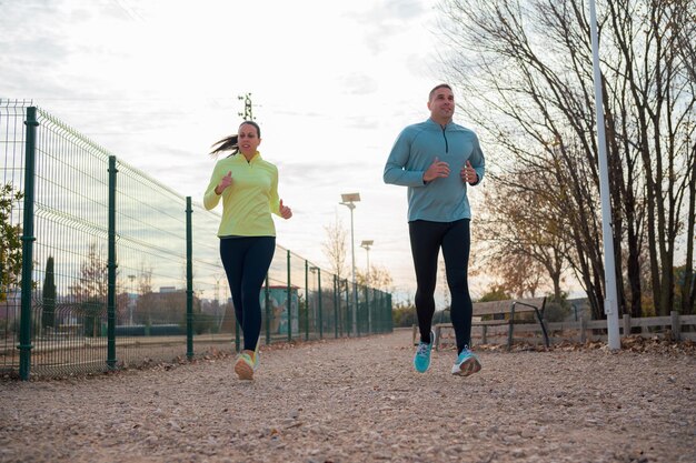 Photo a man and a woman running in a park