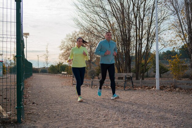 Photo a man and a woman running in a park