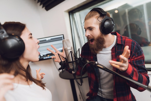 A man and a woman sing a song in a modern recording studio 