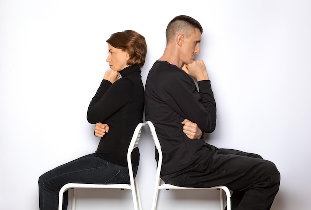 A man and a woman sit with their backs to each other.