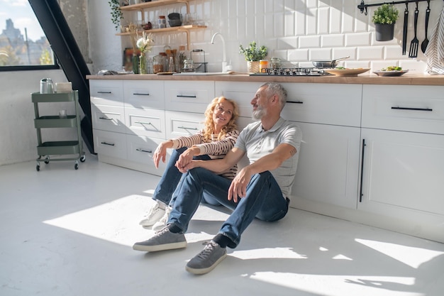 Man and woman sitting on the floor in the kitchen and looking relaxed