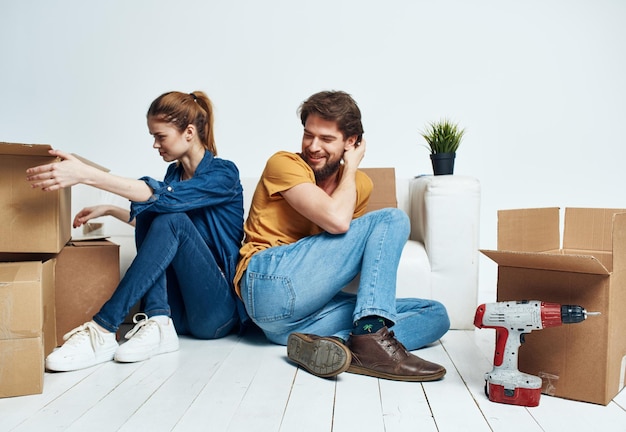 Man and woman sitting on the floor with their backs to each other renovation work moving a flower in a pot