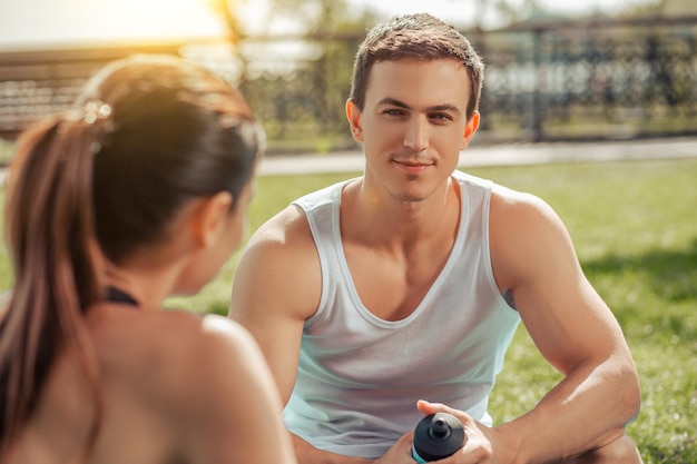 Man and woman sitting in the park after exercising at daylight