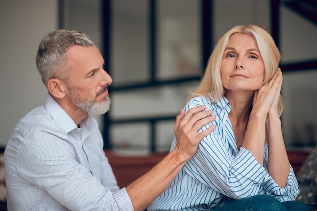 Man and woman sitting on the sofa and looking thoughtful