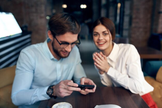 Foto uomo e donna seduti al tavolo vicino alla comunicazione telefonica di colleghi di lavoro foto di alta qualità