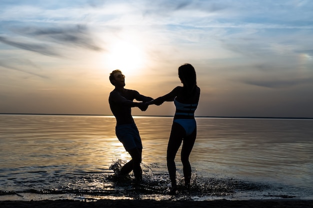 The man and woman spinning in circle against the beautiful sunset