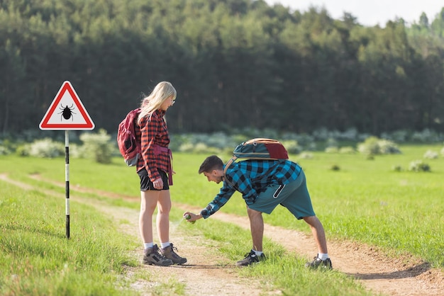 Photo man and woman spraying with tick repellent in nature