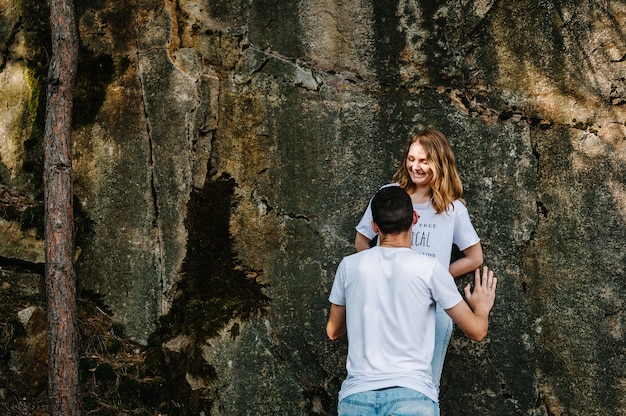 Man and woman stand back near a large rock