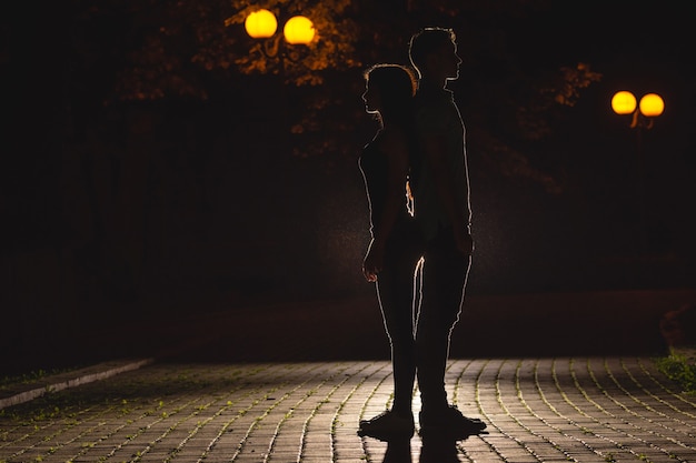 The man and woman stand on the dark street. night time