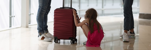 男と女はスーツケースを持って子供の真ん中で互いに距離を置いて立っています