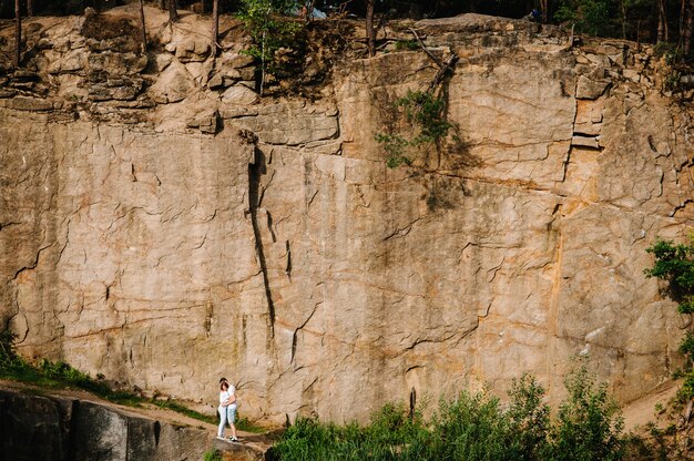 Man and woman stand and hugs on the surface of rocks