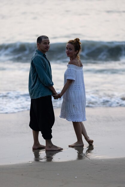 A man and a woman standing on the beach in front of the ocean