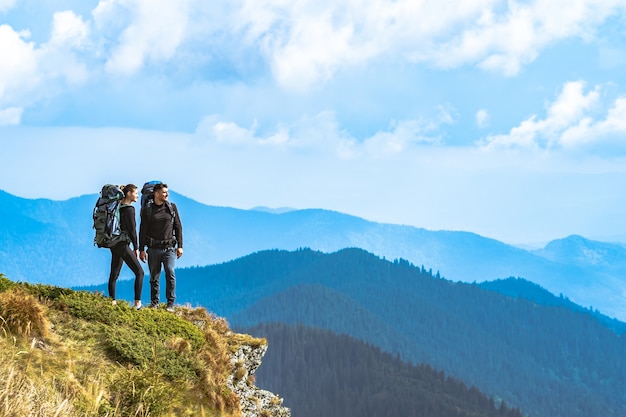 The man and a woman standing on the cliff with a beautiful view