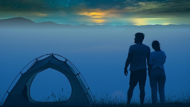 The man and woman standing on a mountain top at the campsite