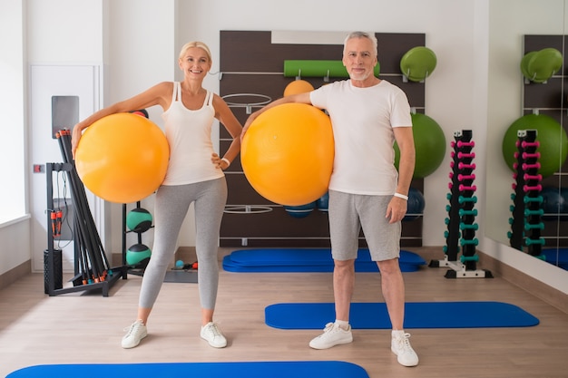 Man and a woman standing with fitballs