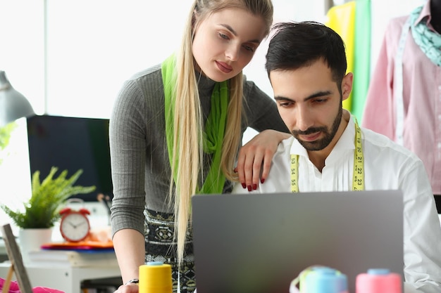 Il designer di stilista uomo e donna lavora su un client di consulenza per laptop online in officina