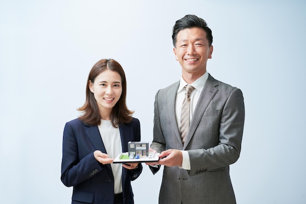 Man and woman in suits with house model