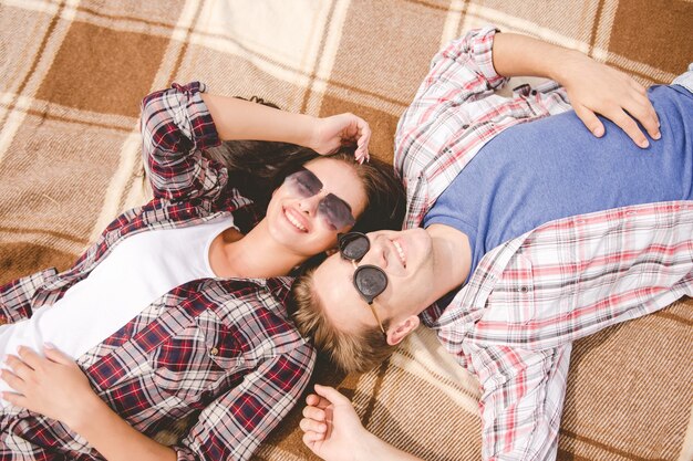 The man and woman in sunglasses lay on the ground