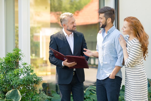 Photo a man and a woman talk to a man in a suit outside a house.