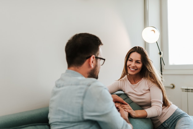 man and woman talking while relaxing on the couch in the living room.