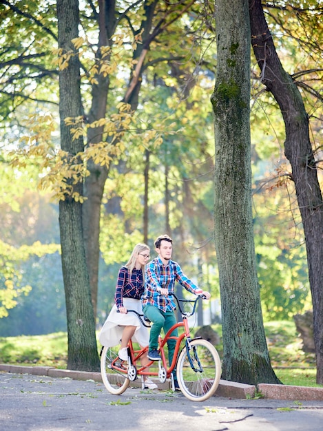 man and woman on tandem bike in park