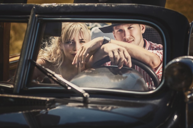 Photo man and woman together at the wheel of old black car