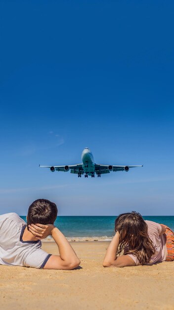 Man and woman tourists have fun on the beach watching the landing planes traveling on an airplane