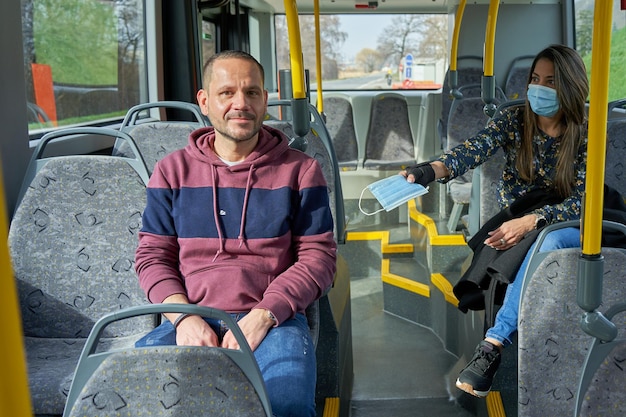 Man and woman travel in to the bus with a mask