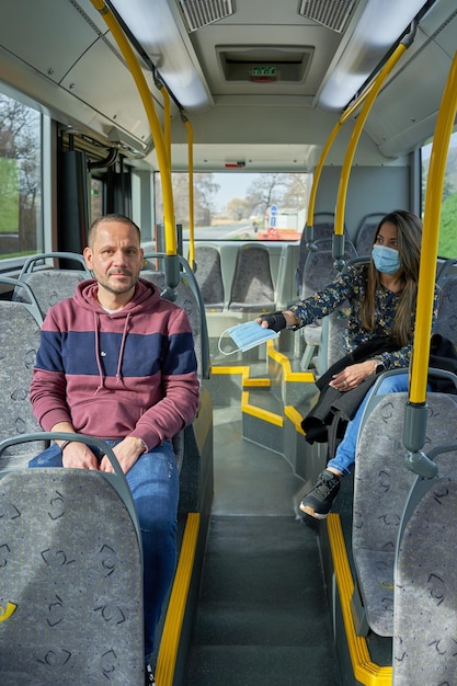 Man and woman travel in to the bus with a mask