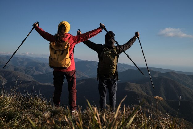 黄色のバックパックを持った男性と女性の旅行者は背中を持って立っています山を旅する