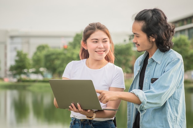 Uomo e donna che utilizzano la tecnologia aziendale del computer all'aperto