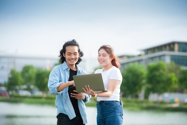 Man and woman using laptop computer sitting outdoor