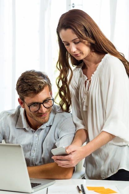 Uomo e donna che utilizza telefono cellulare nell'ufficio