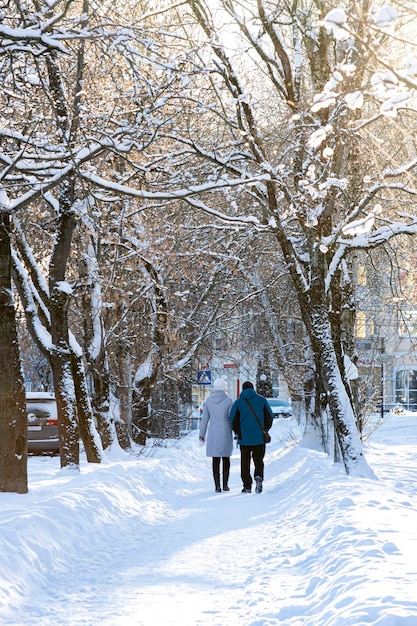 Man and woman walk along snowy street after heavy snowfall