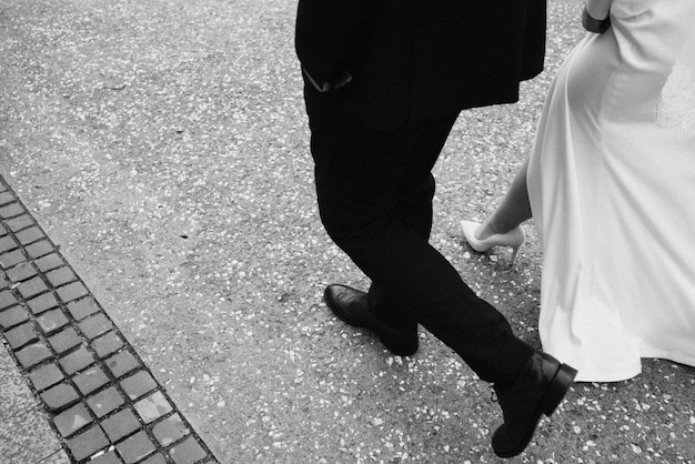 A man and woman walk down a sidewalk, wearing black shoes.